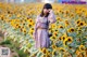 A woman standing in a field of sunflowers talking on a cell phone.