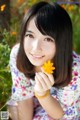 A woman holding a yellow flower in her hand.