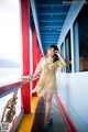 A woman in a yellow dress standing on a boat.