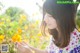 A woman holding a yellow flower in a field of flowers.