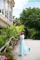 A woman in a blue dress standing in front of a building.