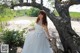 A woman in a wedding dress leaning against a tree.