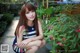 A woman sitting on the ground next to a potted plant.