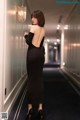 A woman in a black dress standing in a hallway.