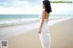 A woman in a white dress standing on a beach.