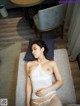 A woman laying on top of a bed in a white lingerie.