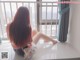 A woman sitting on a window sill looking out a window.