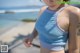 A woman with a tattoo on her arm standing on a beach.